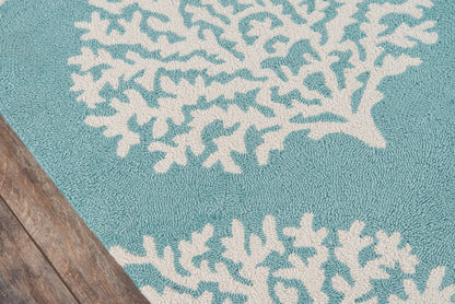 Teal rug with white coral reef pattern, textured loop pile; coastal decor on wooden floor.