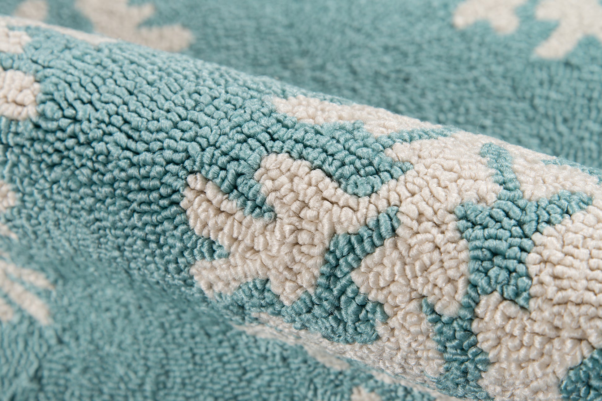 Close-up of teal plush towel with white floral motif; thick looped pile, cozy home bath decor.
