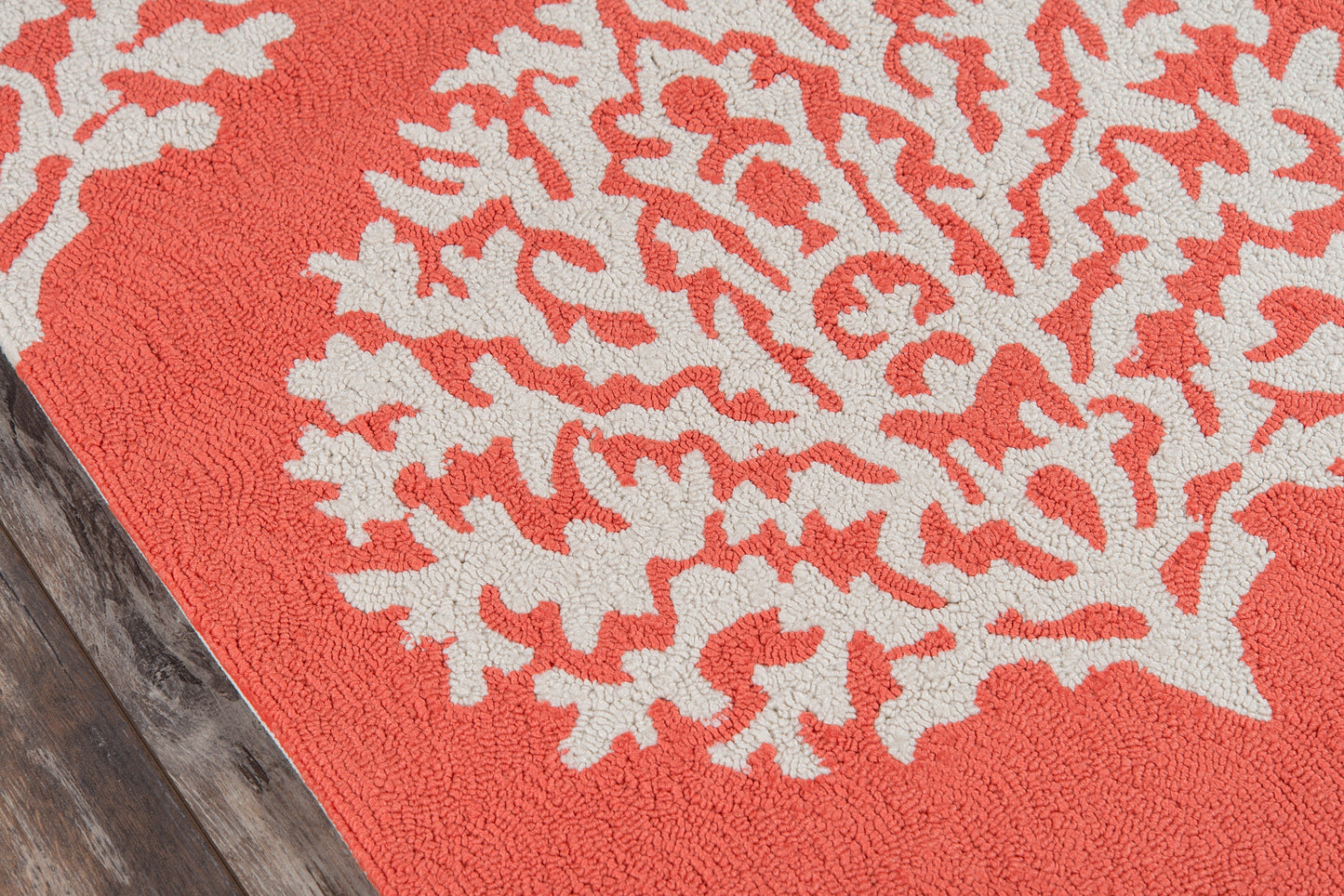Red 9' round rug with a white coral-pattern motif on a wooden floor