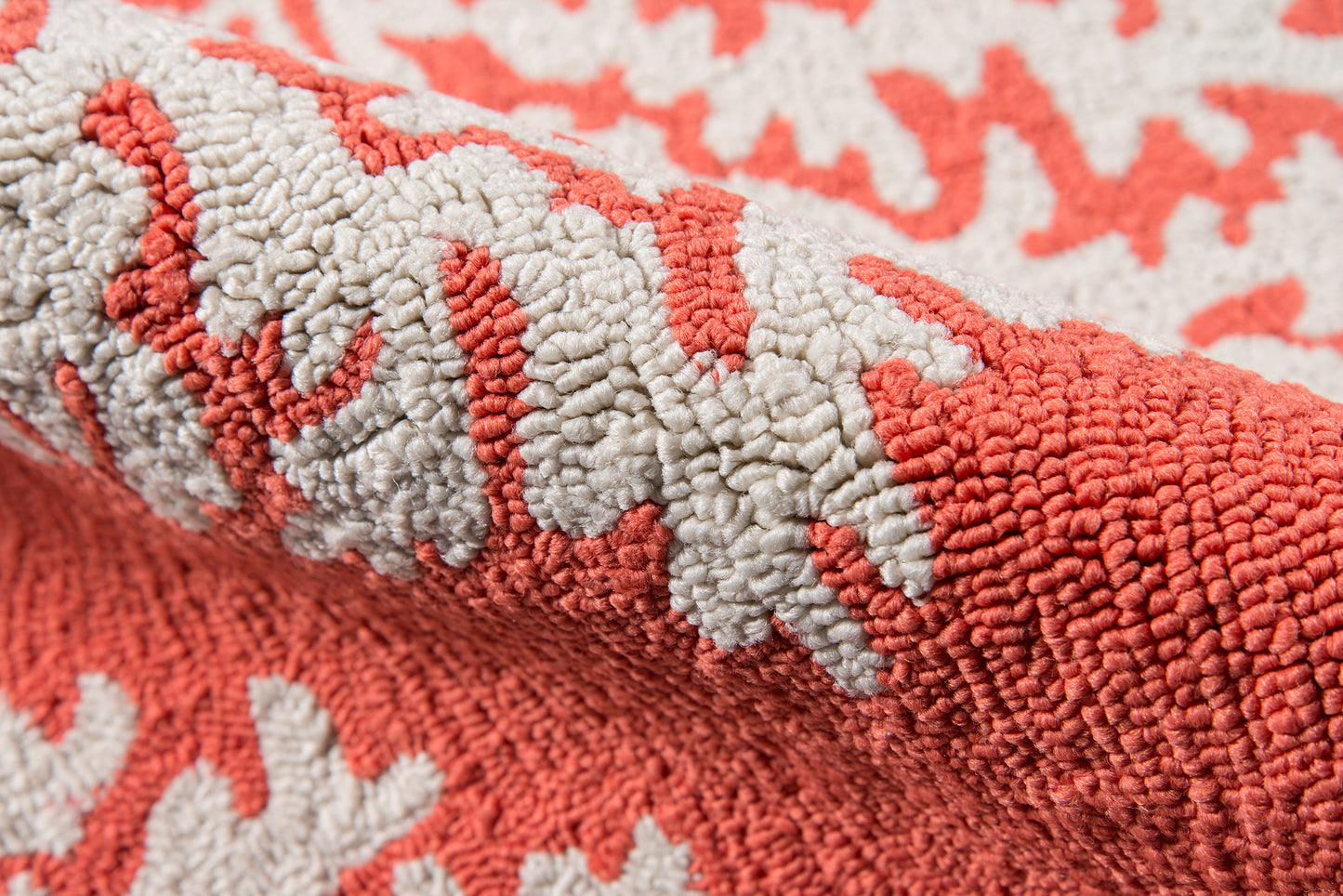 Close-up of coral and ivory loop-pile rug with thick textured fibers; rolled edge, cozy home decor.