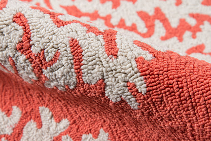Close-up of coral and ivory loop-pile rug with thick textured fibers; rolled edge, cozy home decor.