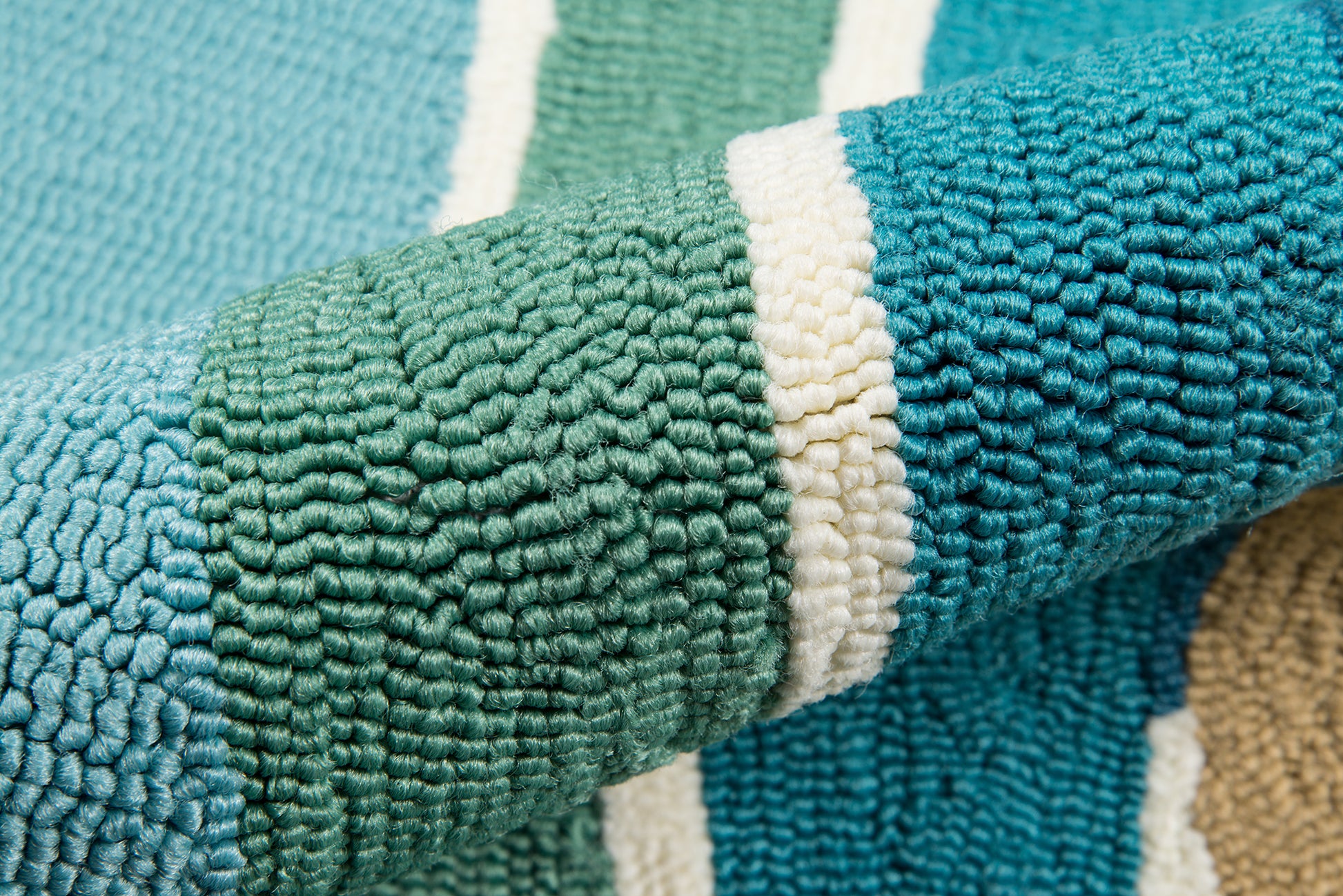 Close-up of a teal and green striped terry towel with a white stripe, soft looped fabric for bath or beach use.