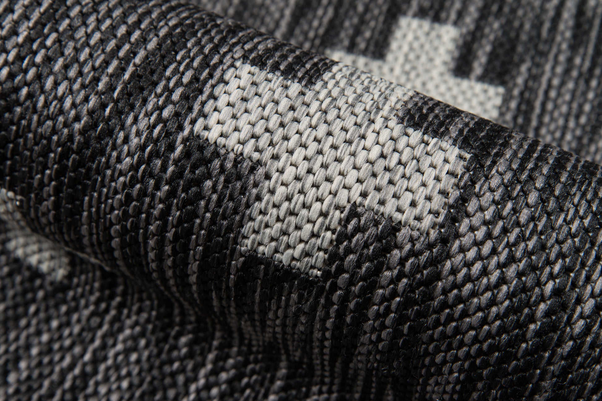 Close-up of dark gray woven canvas fabric with light gray pixelated camo pattern; rugged upholstery textile.