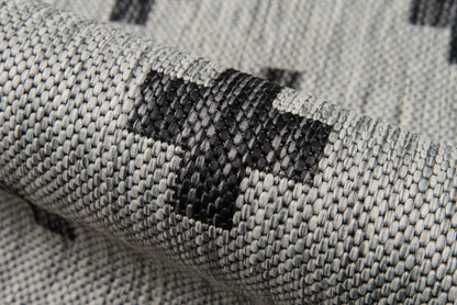 Gray woven rug with dark gray geometric blocks; textured, durable floor decor.