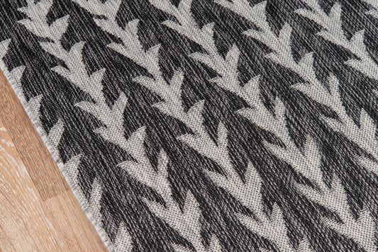 Woven rug with bold black and white chevron pattern; textured fabric on wood floor, modern geometric style.