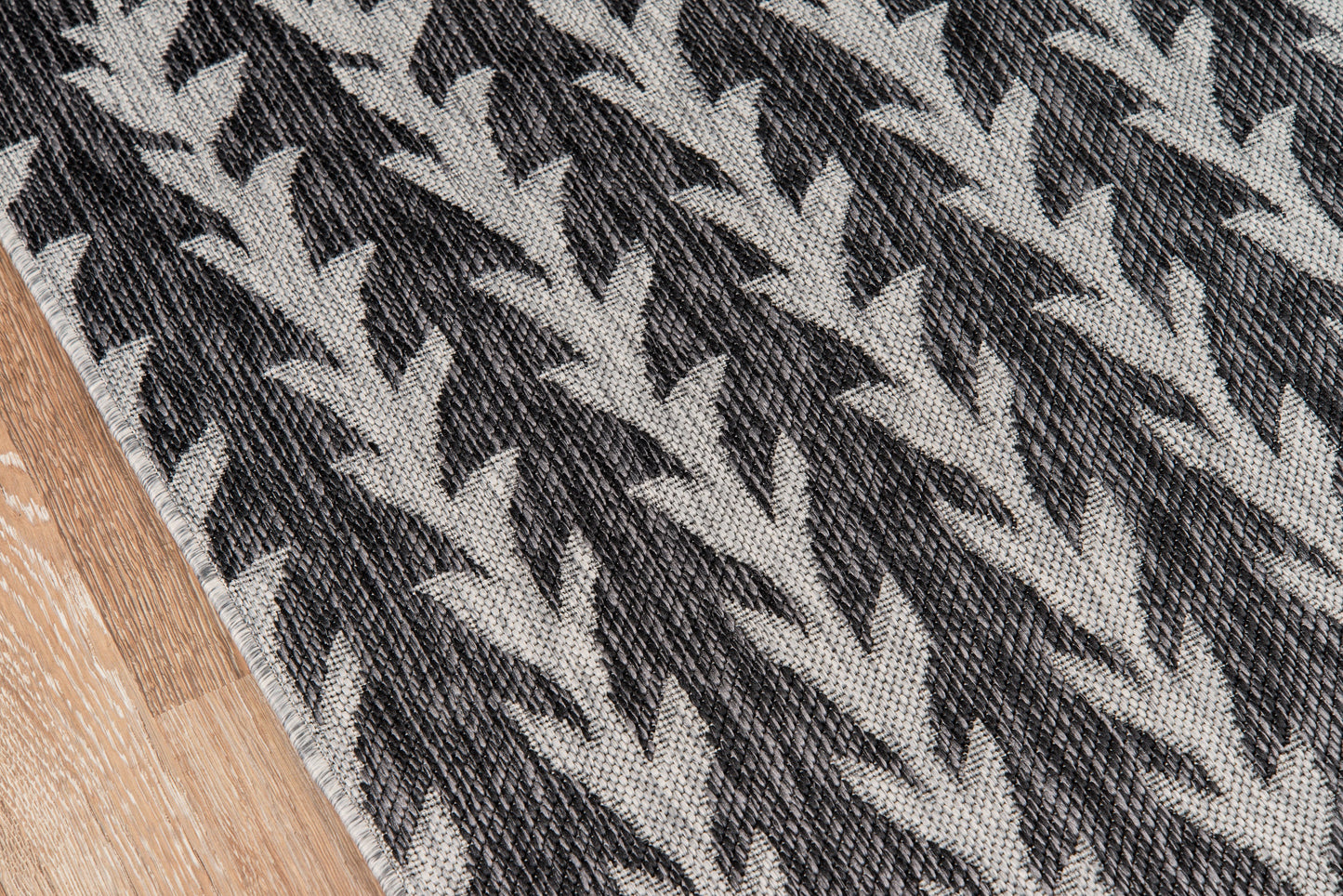 Gray and charcoal chevron woven rug with textured surface on wood floor, 9' x 13'.