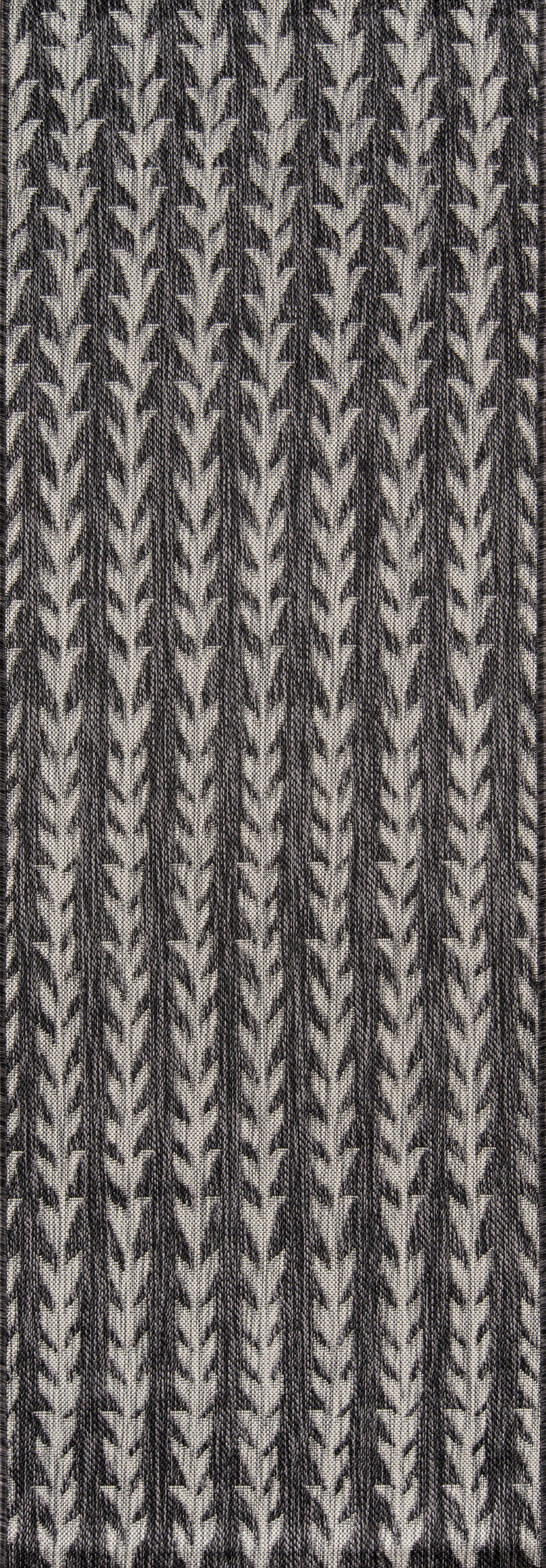 Close-up of rug texture with vertical charcoal chevron leaf motifs on a light gray background.