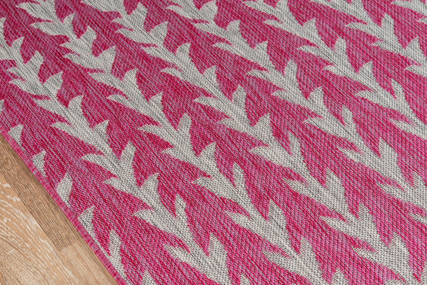Pink woven runner with beige chevron pattern; textured textile on wood floor, edge visible.