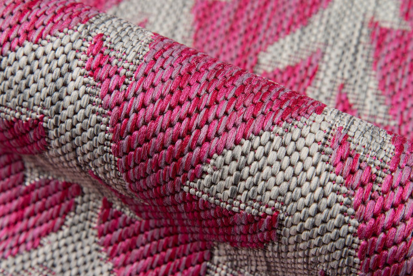Close-up of pink and beige woven rug with a geometric damask pattern and textured surface, a runner rug.