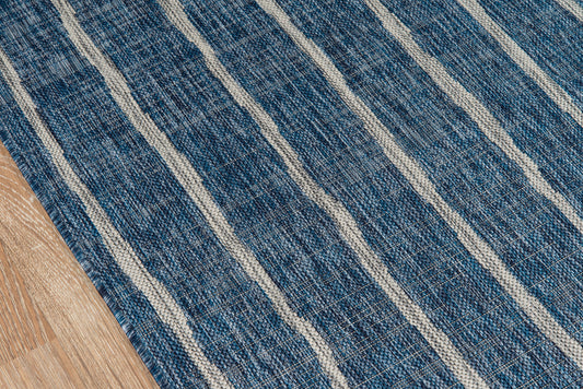 Blue woven rug with cream diagonal stripes on a wooden floor.