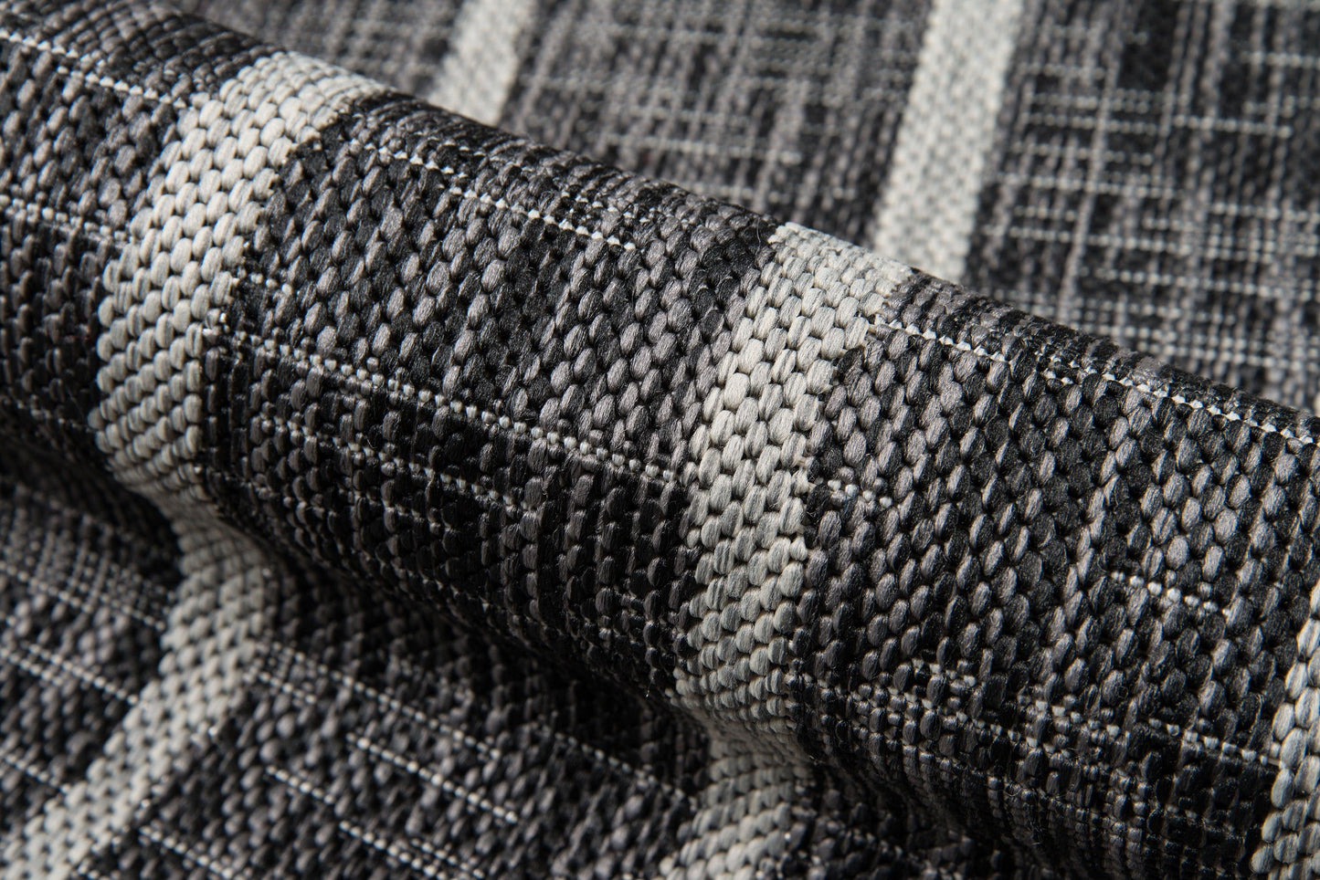 Rolled charcoal gray and white woven textile with a thick textured plaid pattern; ideal rug or throw.