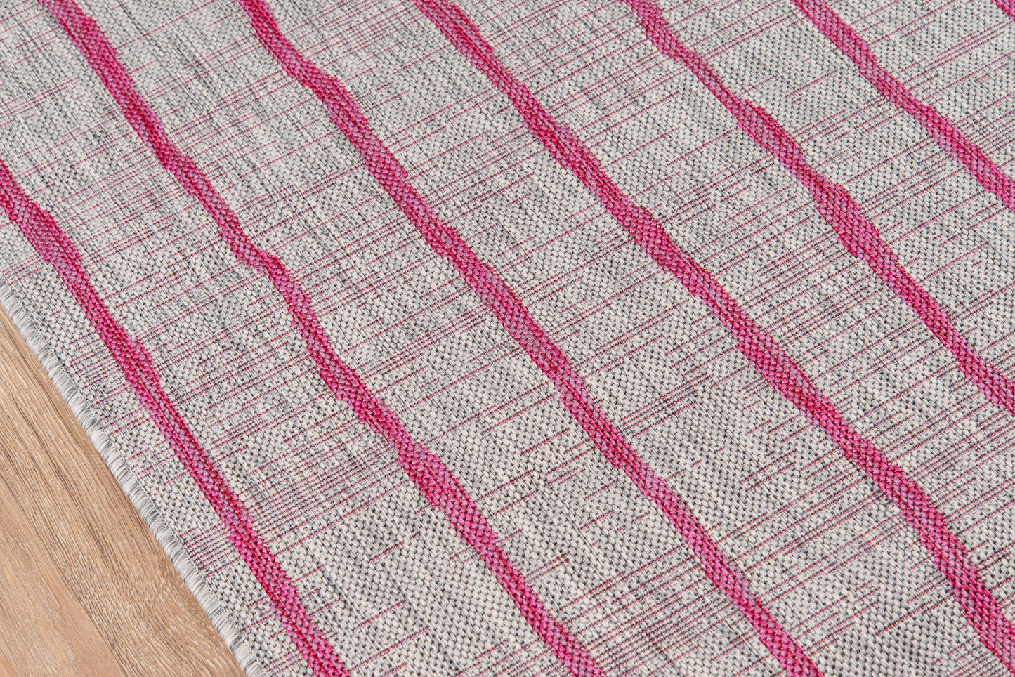 Beige woven rug with bold pink diagonal stripes on a wood floor