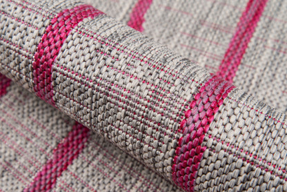 Close-up of beige woven rug with magenta pink stripes; textured, tightly woven fibers.
