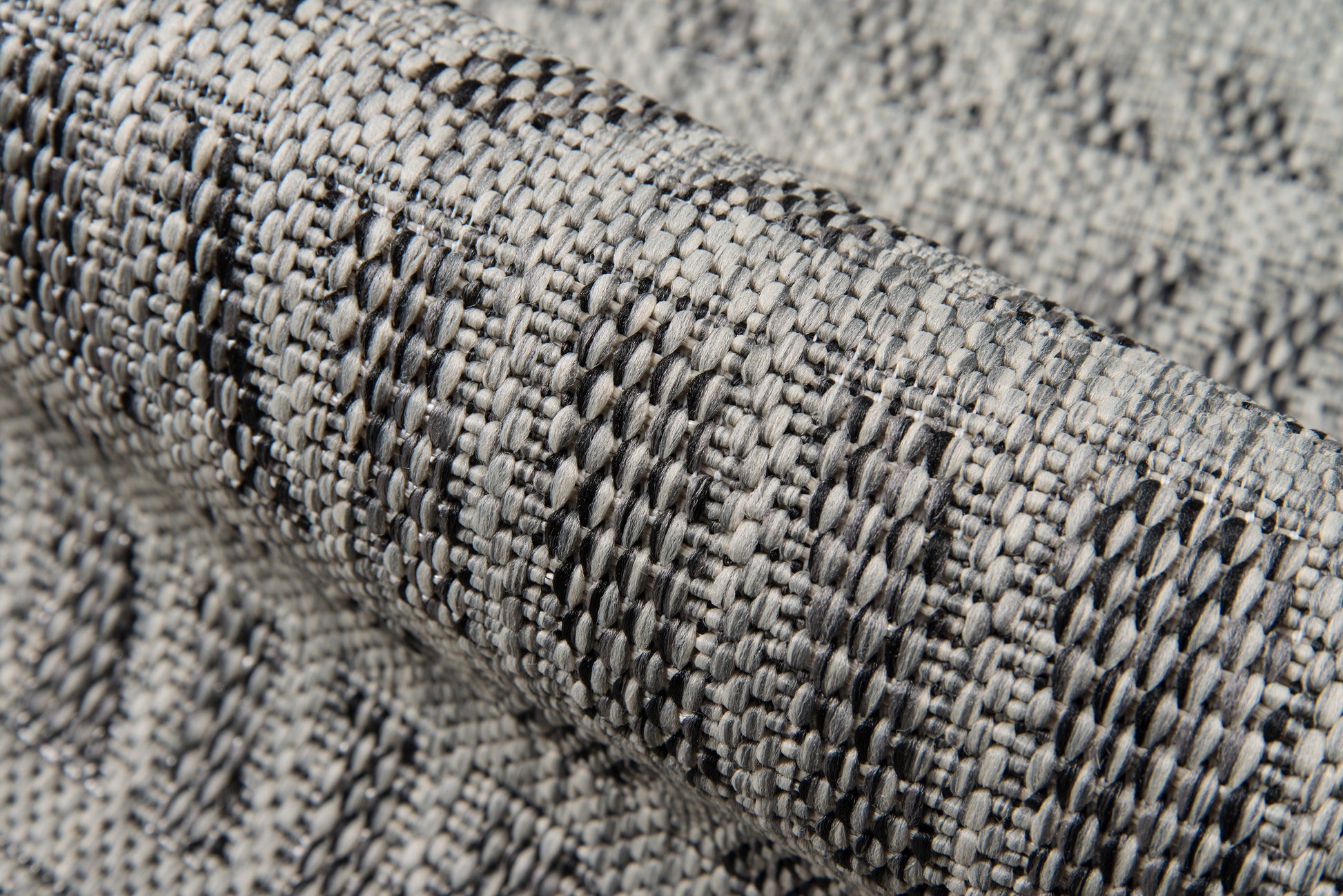 Gray and charcoal woven rug fabric with textured looped threads and subtle chevron pattern.