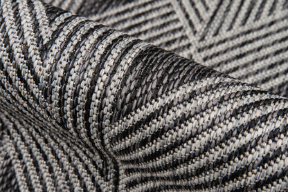 Close-up of charcoal gray and white woven fabric with striped chevron pattern, textured textile for scarves or upholstery.