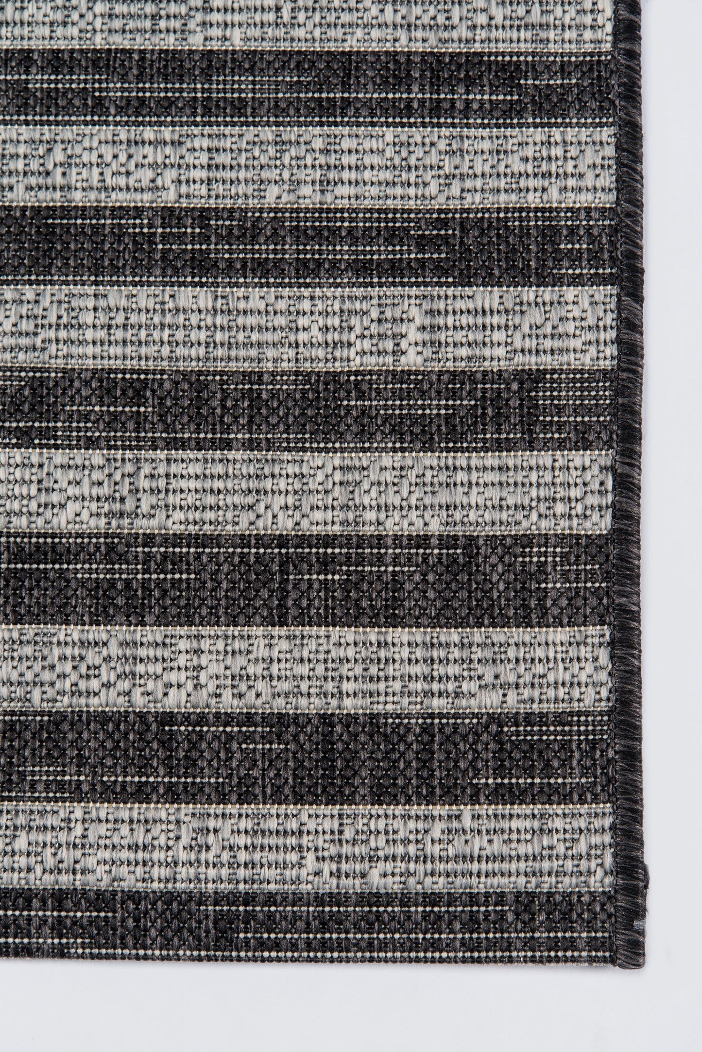 Woven rug with alternating charcoal and light gray stripes; dense weave, rectangular, modern minimalist style.