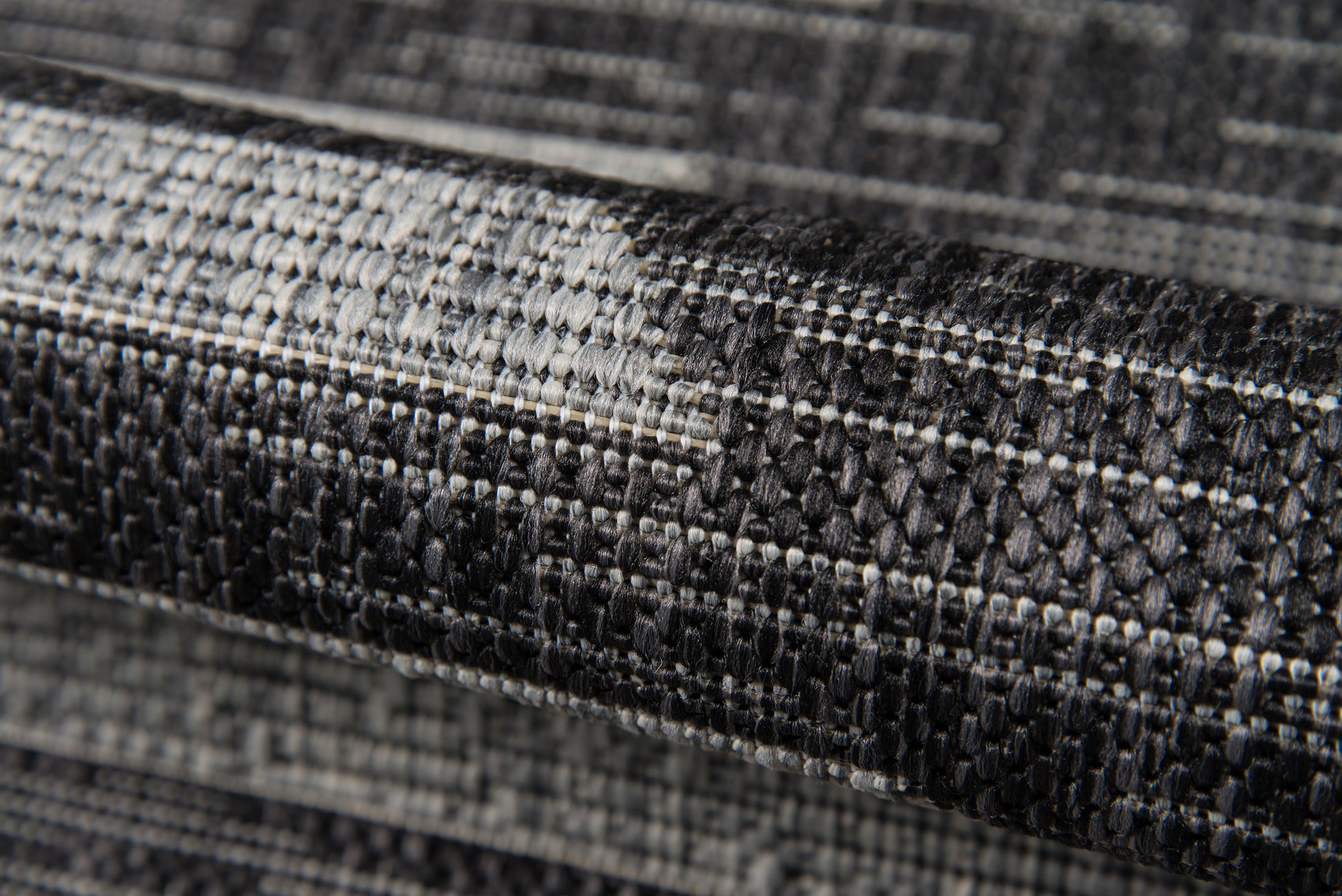 Dark gray & black woven rug with textured geometric pattern and looped pile.