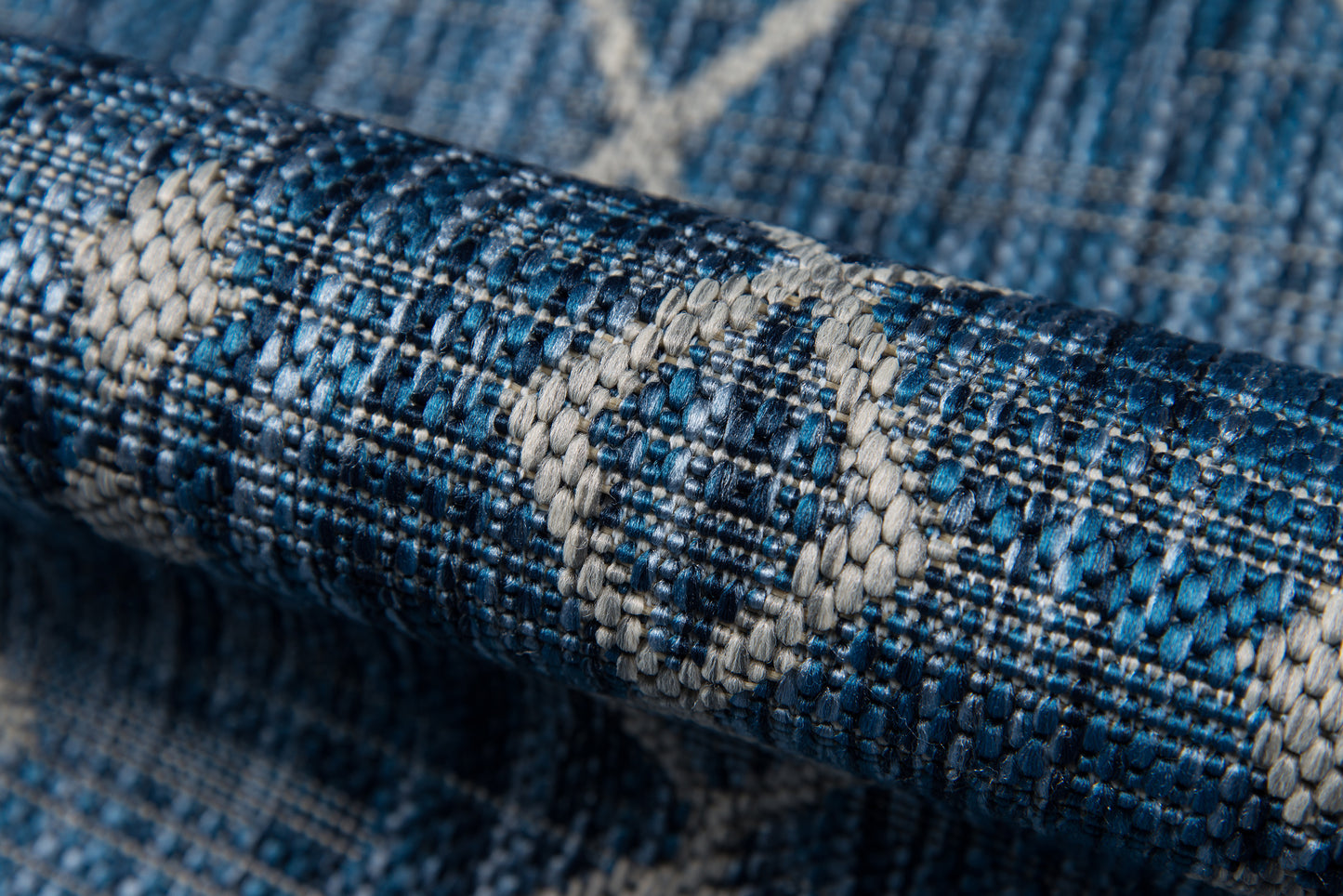 Close-up of blue woven rug with white diamond motifs and textured geometric pattern.