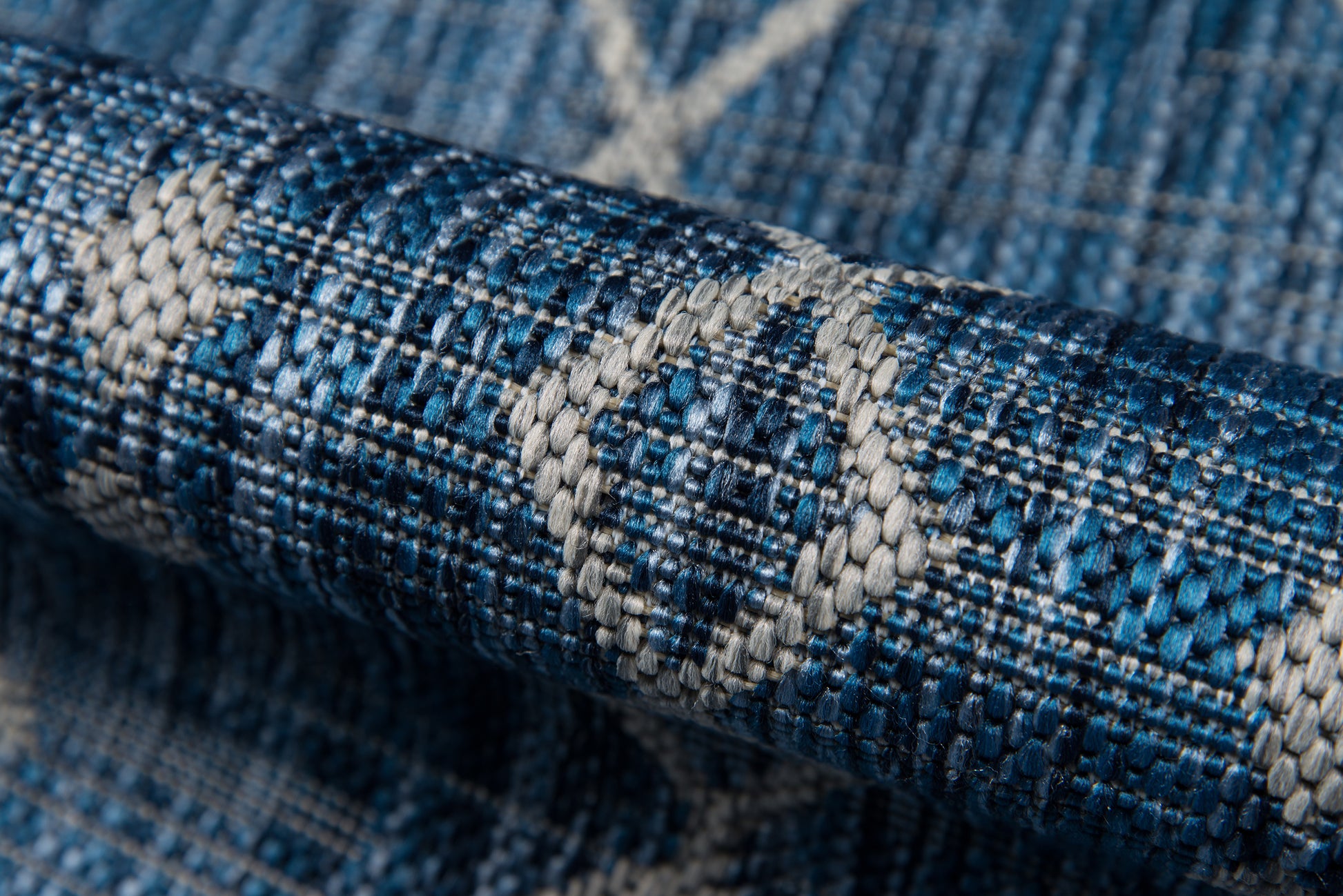 Close-up of blue woven fabric featuring white diamond motifs, textured textile suitable for rug or upholstery.