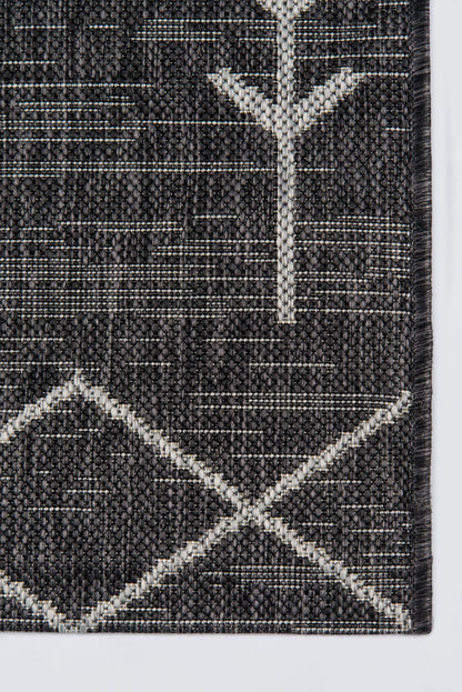 Charcoal grey rug with white geometric tree motif and intersecting diamond patterns; woven loop-pile.