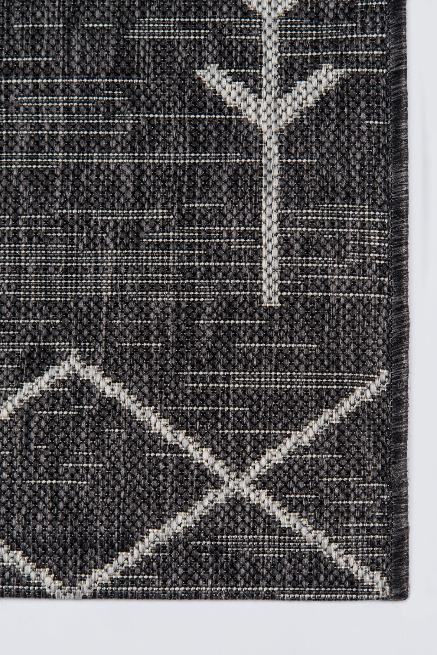 Dark gray woven rug with white geometric motifs: a tree-like Y near the top and a white diamond lattice at the bottom.