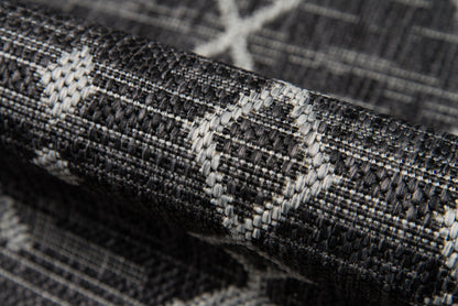 Close-up of dark grey woven rug with light grey diamond pattern and textured weave.