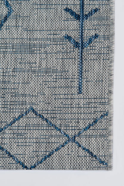 Gray woven rug with blue geometric diamonds and a tree-like motif; textured textile for decor.