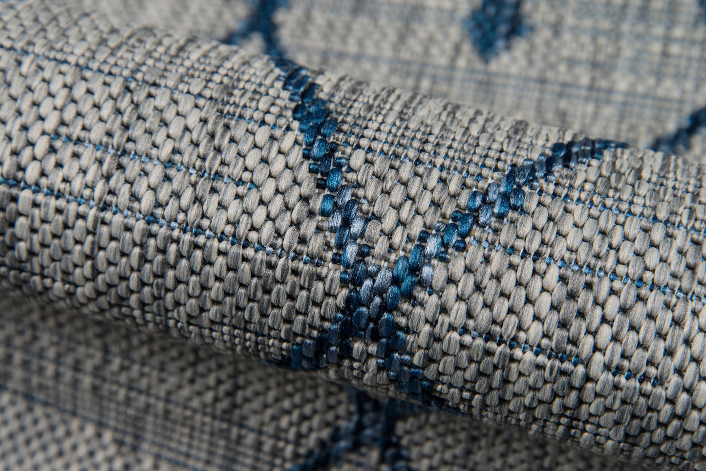 Gray woven fabric with blue thread lines, a textured upholstery textile suitable for décor.