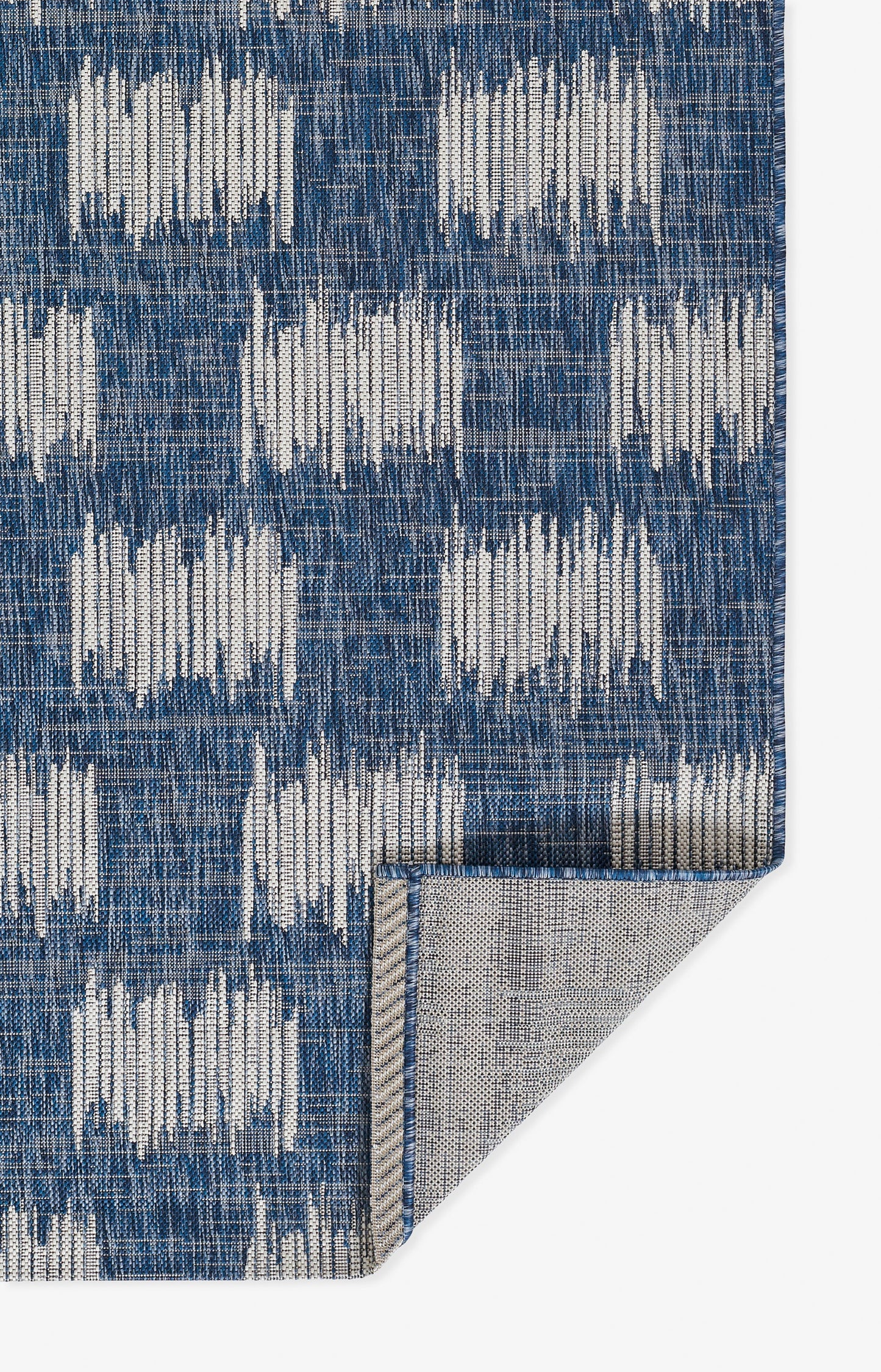 Blue woven rug with white geometric blocks; textured fabric, ikat-inspired pattern for living spaces.