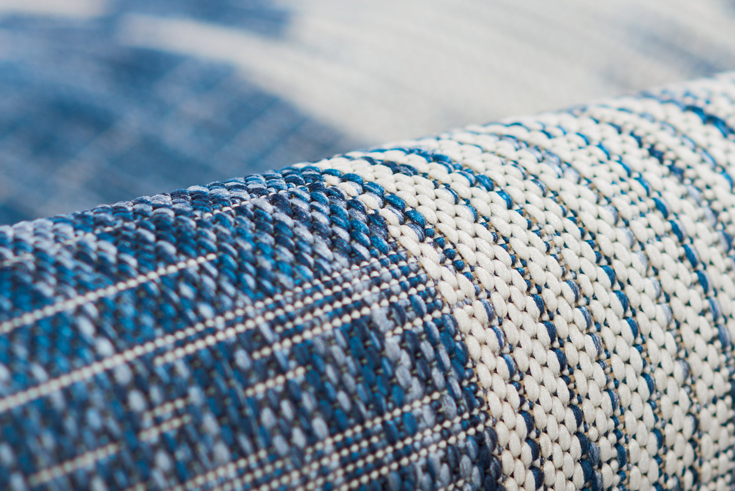 Close-up of blue and white striped woven rug with thick, textured weave.