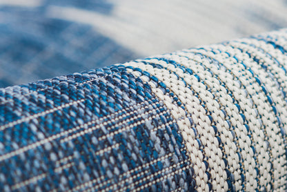 Close-up of blue and white braided rug with nautical striped pattern, tightly woven and rolled.