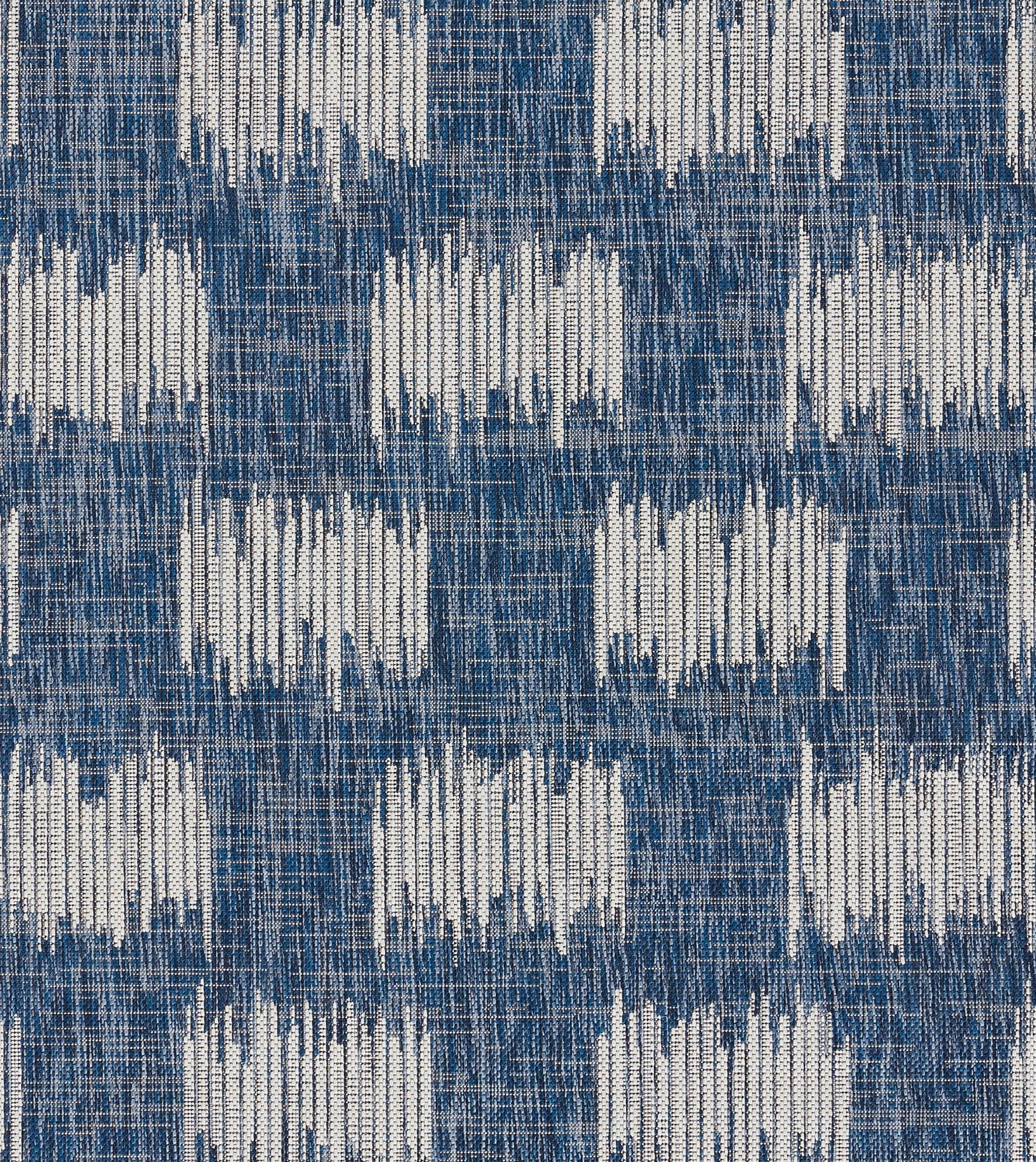 Blue woven fabric with white geometric blocks in a repeating ikat-style grid; denim-like textured textile.