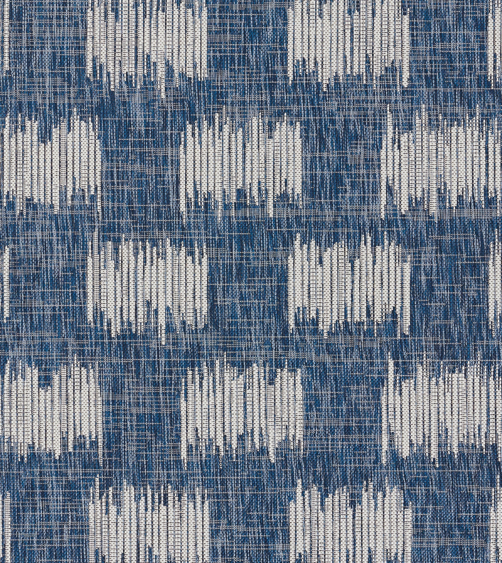 Blue woven rug with white geometric blocks in ikat-inspired pattern; 5' x 8'.