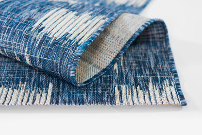 Blue & white woven rug runner with abstract striped pattern; rolled edge reveals beige underside; size 2' x 6'.