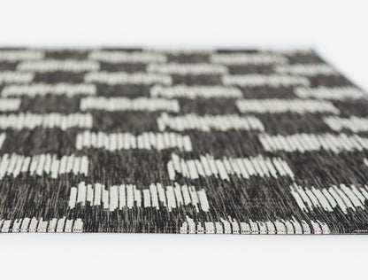 Flat-weave runner rug in charcoal and white with geometric checker blocks; modern, durable decor for living room or hallway.