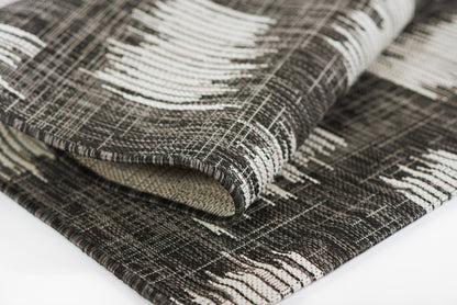 Dark brown and cream geometric woven rug with thick textured weave, neatly folded.