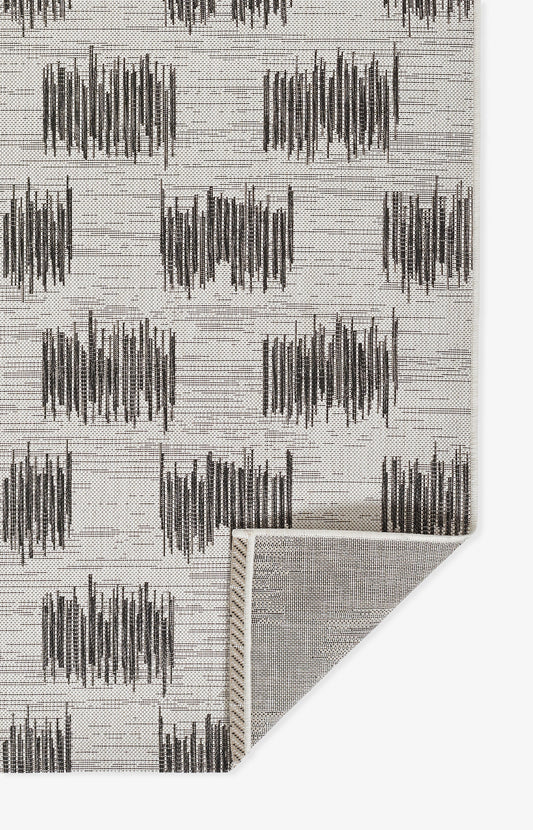 Rug with light gray base and dark charcoal abstract vertical blocks; rectangular, modern geometric pattern.