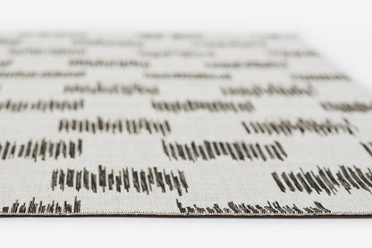 Close-up of a white rug with a black geometric print and woven texture; rectangular swatch for home decor, 2' x 3'.