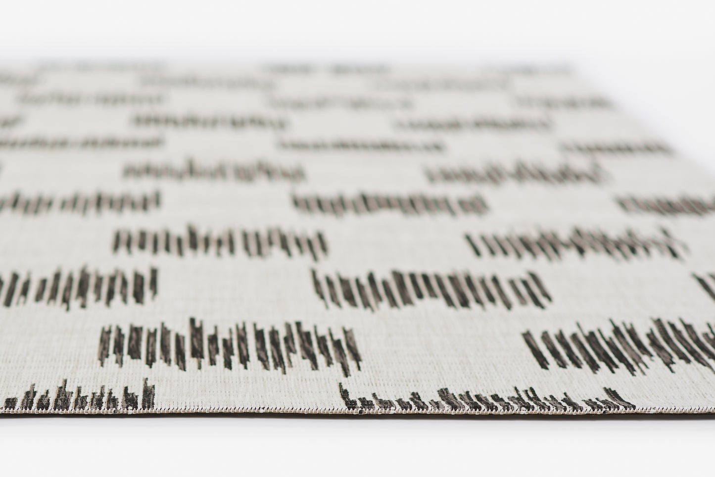 Close-up of white rug with a black geometric pattern; shallow depth of field, edge of the rug visible.