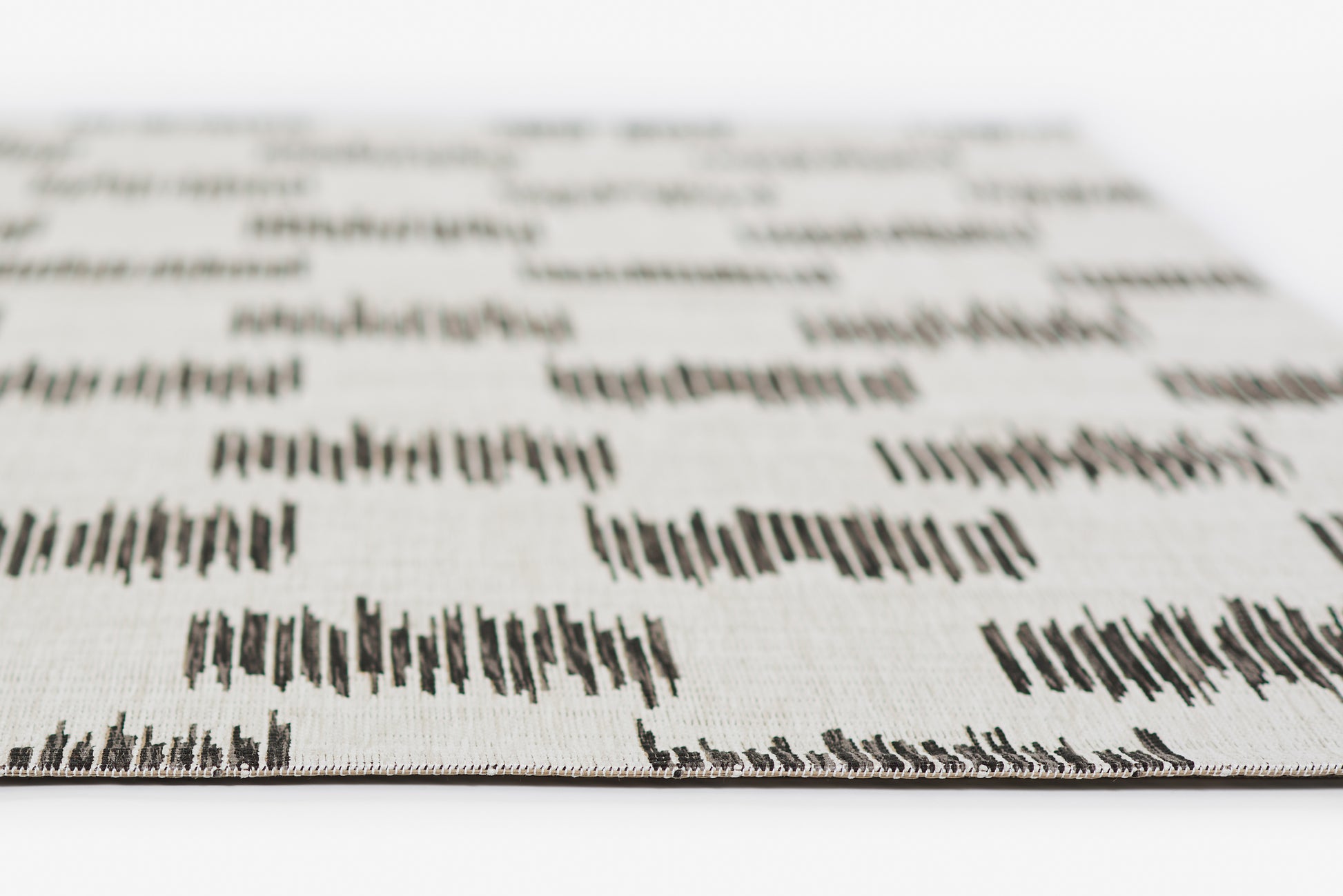Ivory woven fabric with black geometric ikat-style pattern; close-up texture, ideal for upholstery or home décor.