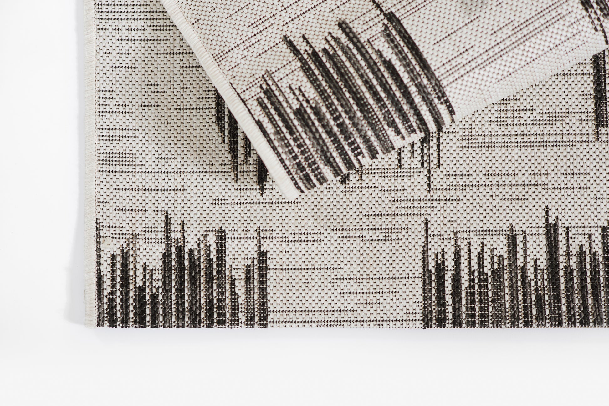 Cream woven rug runner with black vertical bar pattern; folded corner visible.
