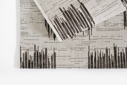White woven area rug with a black skyline pattern; modern, folded corner.