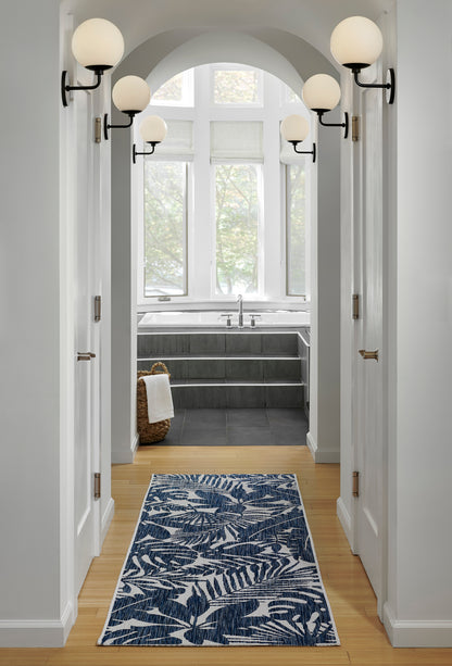 Hallway scene with an arched doorway, globe sconces, white walls, and a blue fern-pattern runner rug (2' x 6').