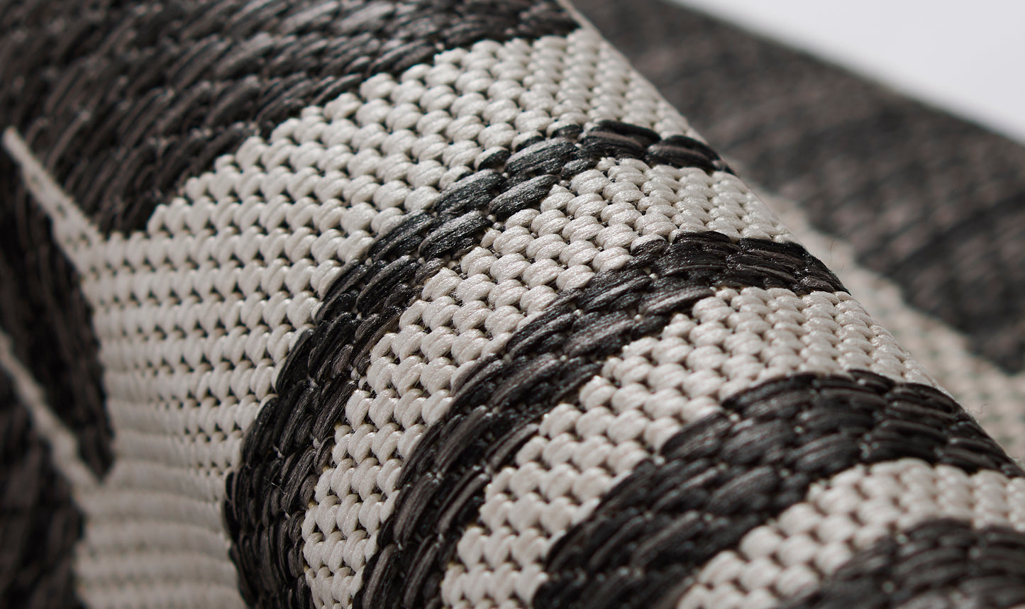 Close-up of a black and natural striped woven rug runner.