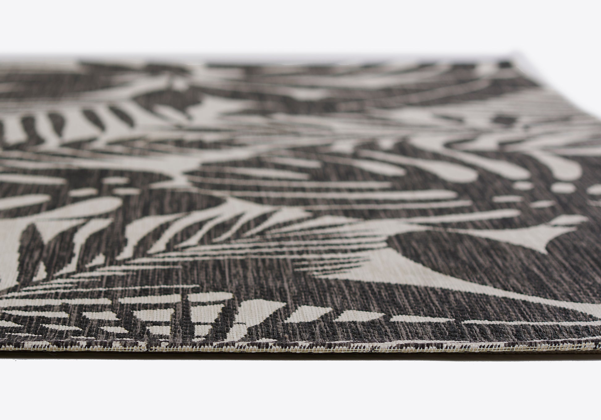 Close-up of a black-and-white botanical rug with a palm leaf pattern; flat-weave texture, modern decor accent