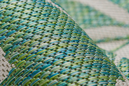 Close-up of green and teal woven rug texture on a curved surface.