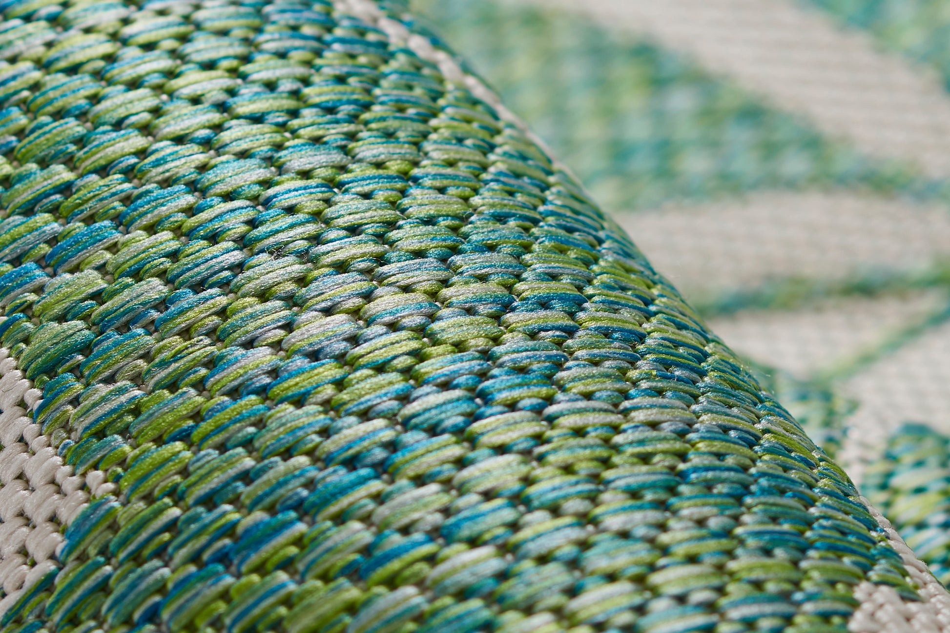 Close-up of a green and turquoise braided straw weave with a rich texture on a rug.