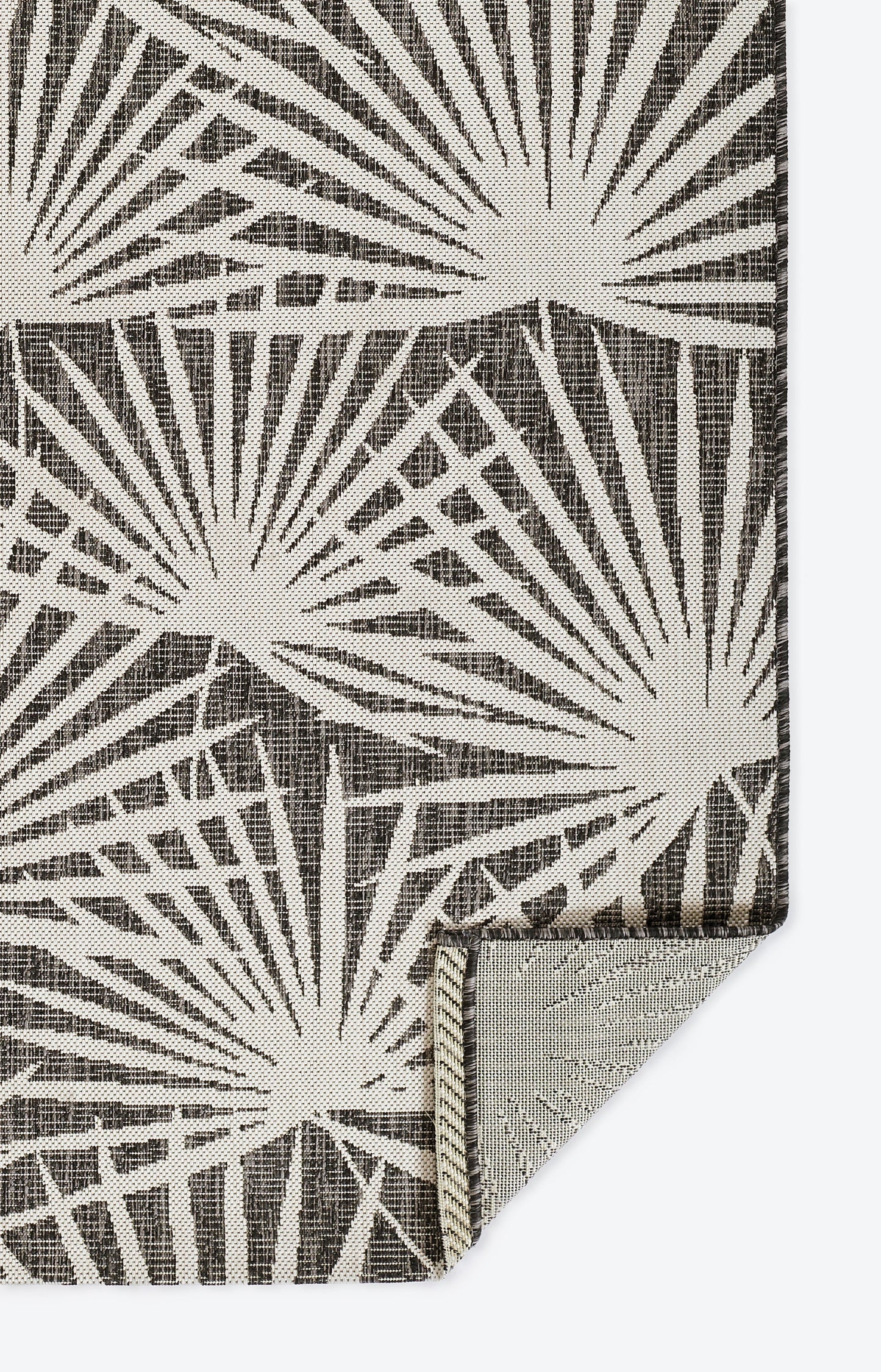 Textured fabric swatch with cream sunburst geometric pattern on brown; folded corner reveals lighter underside.