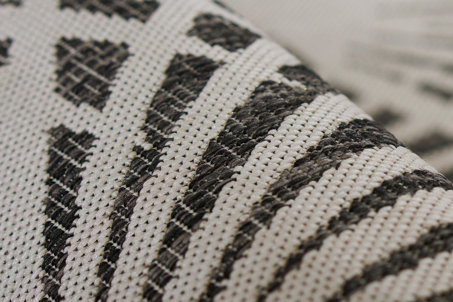 Close-up of cream woven rug with black geometric stripes; textured textile.