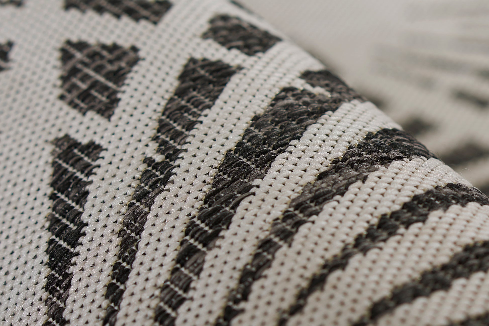 Close-up of black & white striped woven rug runner with geometric shapes; soft textile texture.